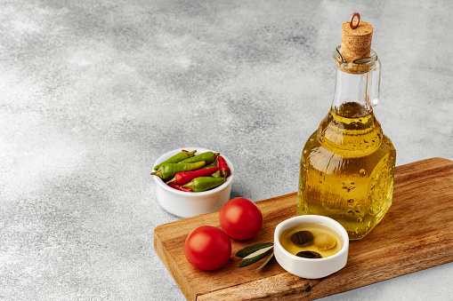 Natural fresh olive oil in bottle on gray table, close up