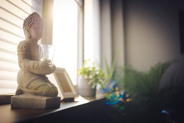 Zen spiritual ritual meditating white face of Buddha, brown candle on green floral background. Religion concept, esoterics. Still life style. Home decor. Place for text, copy space. Spiritual awakening