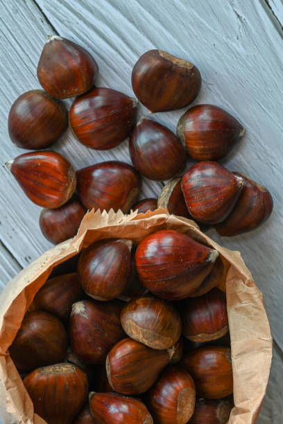 istock Chestnuts in a paper bag on a wooden background 1364572536