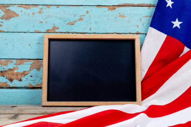 istock Blank writing slate with copy space by usa flag on blue wooden table 1364574649