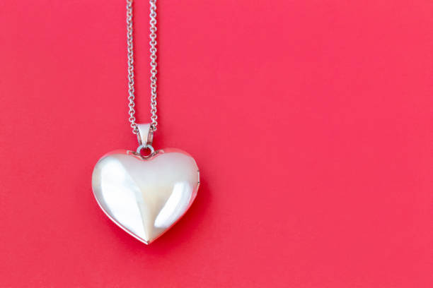 Heart pendant on a chain on a red background Two heart pendants on a chain on a red background right and left, Valentine's day, flat lay, copy space locket stock pictures, royalty-free photos & images
