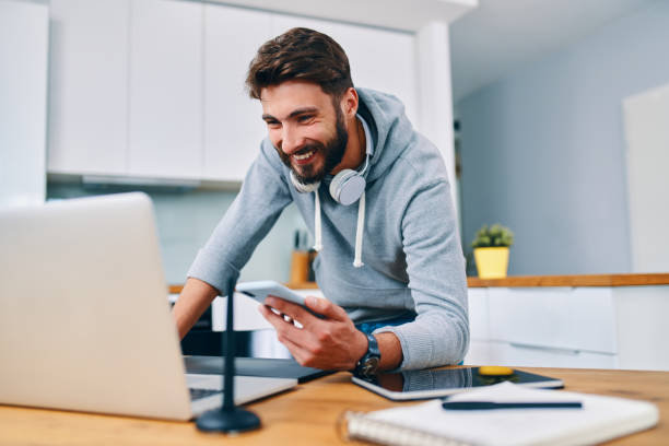 istock Web designer leaning on desk and checking work on laptop and smartphone 1364578604