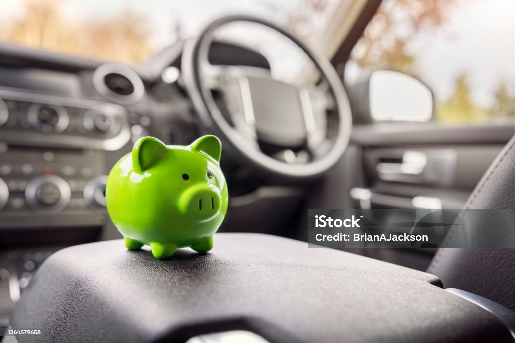 Green piggy bank money box inside car, vehicle purchase, insurance or driving and motoring cost Green piggy bank money box in car interior, vehicle purchase, insurance or driving and motoring cost Car Stock Photo