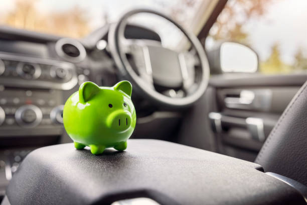 Green piggy bank money box inside car, vehicle purchase, insurance or driving and motoring cost stock photo