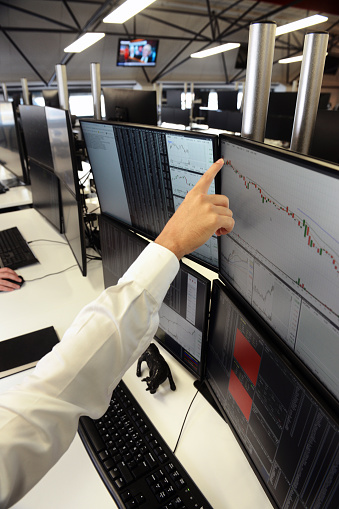 Stockbroker team keeps track of developments in a multi-screen office