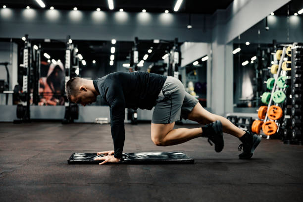 istock A fit man does warm-up exercises on a mat in a gym. 1364581028
