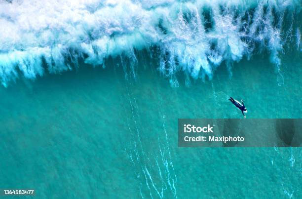 Big Wave Splashing Behind A Lonely Surfer Seen From Above Stock Photo - Download Image Now