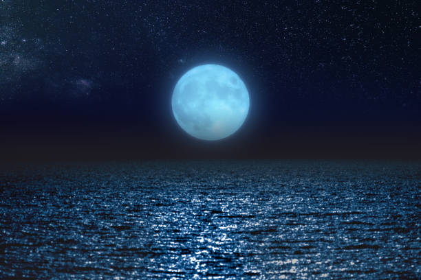 istock Full Moon with starry skies rising above ocean horizon. 1364584397