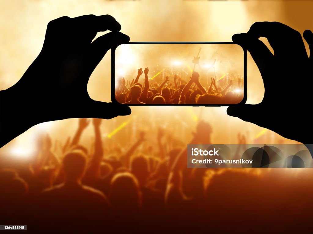 Silhouette of hand using camera phone to take pictures and videos at pop concert. Streaming to internet. Silhouette of hand using camera phone to take pictures and videos at pop concert. Streaming to internet Telephone Stock Photo