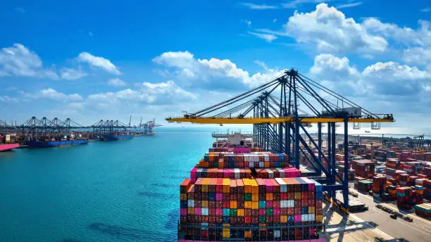 Photo of Aerial view of cargo ship and cargo container in harbor.