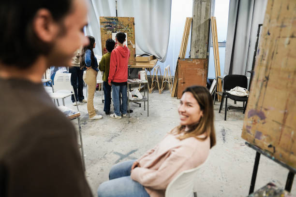 istock Happy friends having fun inside art room class at university - Focus on students painting on background 1364589097
