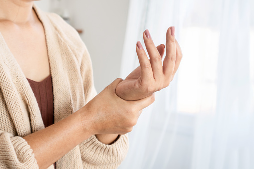 mujer que sufre de dolor en la muñeca, entumecimiento o síndrome del túnel carpiano con la mano sosteniendo su articulación dolorida photo
