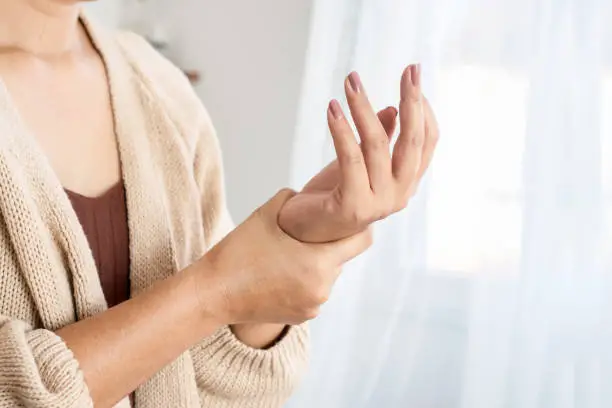 Photo of woman suffering from wrist pain, numbness, or Carpal tunnel syndrome hand holding her ache joint