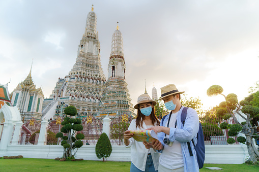 Asian couple happy tourists to travel on they holidays and holding in Wat Arun Temple in Bangkok, Thailand