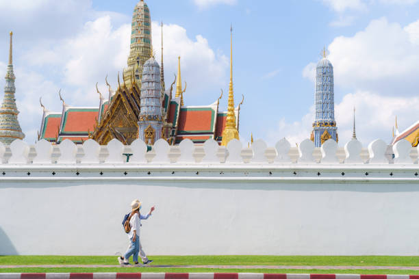 asiatisches paar glückliche touristen reisen mit maske, um sich vor covid-19 zu schützen, während ihres urlaubs im wat phra kaew tempel in bangkok, thailand - bangkok thailand asia temple stock-fotos und bilder