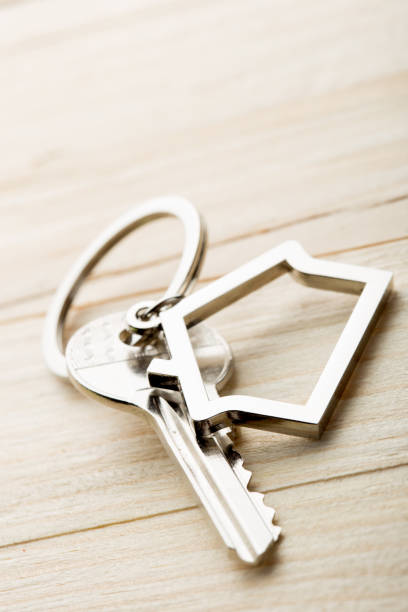 House key with a keychain on wooden desk concept for real estate stock photo