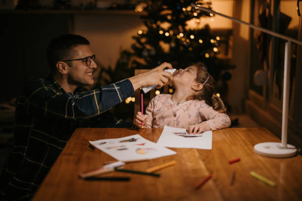 istock Father spraying nasal spray to his daughter's nose while she drawing 1364600668