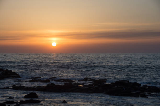 istock Sunset on the horizon and rocky shore 1364601606
