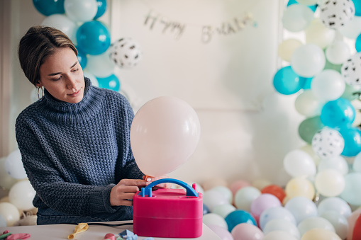 Young woman party decorator , blowing balloons with balloon pump