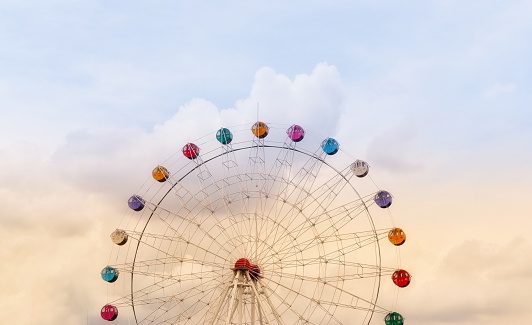 colorful ferris wheel of the amusement park in the cloudy sky background