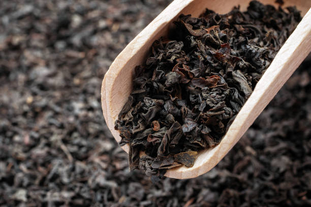 sucha herbata z długimi liśćmi w drewnianej gałce. makro luźnej czarnej herbaty. - dry tea zdjęcia i obrazy z banku zdjęć