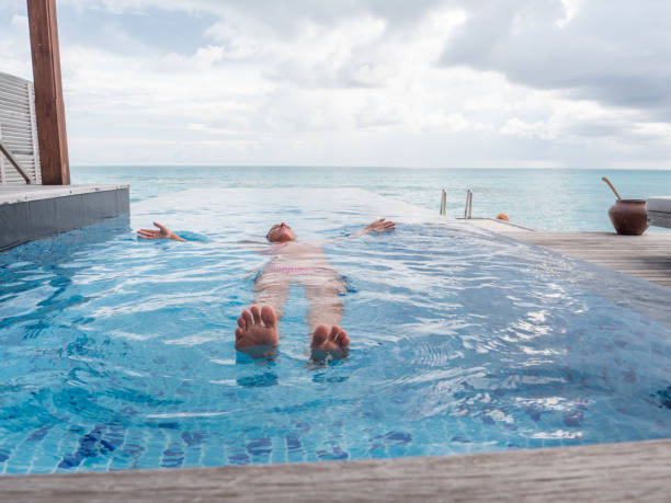 istock Woman floating on infinity pool over lagoon 1364610021
