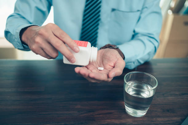 Businessman working with glass of water takes  pills in hand. Working and sick concept. stock photo