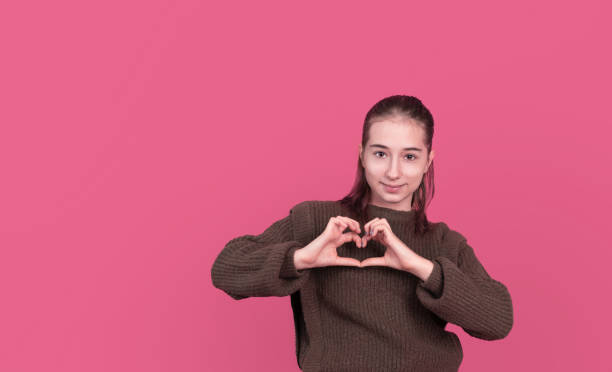 istock Smiling girl showing heart gesture in studio 1364616200