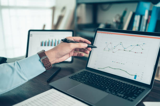 el hombre de negocios sostiene el lápiz óptico y apunta a la computadora portátil en la oficina con un informe de documentos, gráficos, informes financieros en la pantalla. - chart business graph finance fotografías e imágenes de stock