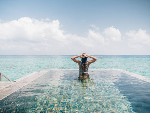 istock Woman relaxes inside infinity pool over reef lagoon 1364617149