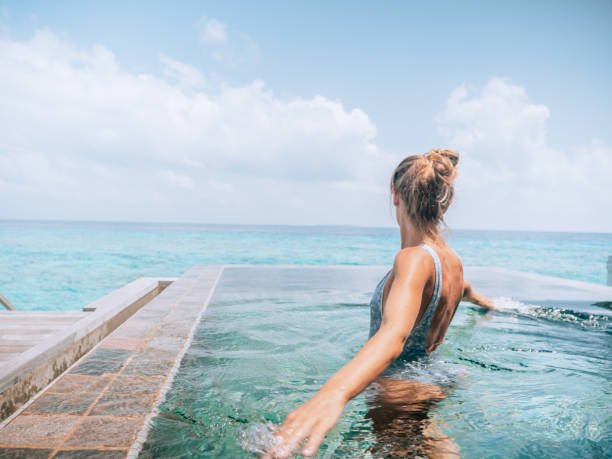 istock Woman relaxes inside infinity pool over reef lagoon 1364617152