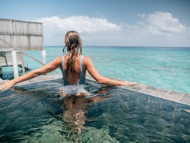 istock Woman relaxes inside infinity pool over reef lagoon 1364617387