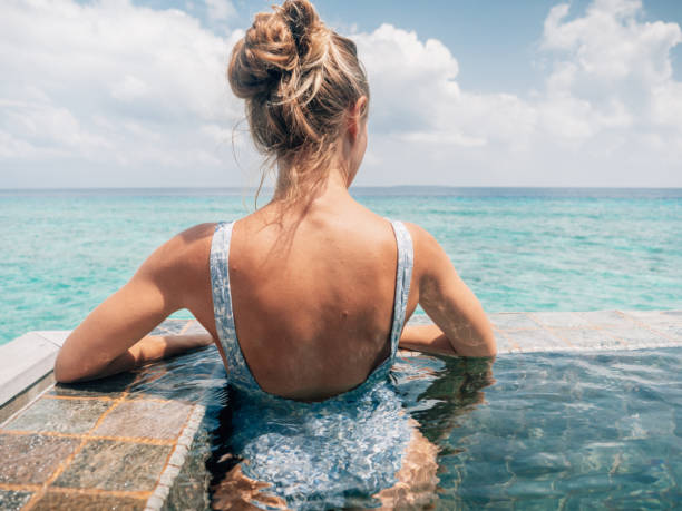 istock Woman relaxes inside infinity pool over reef lagoon 1364617393