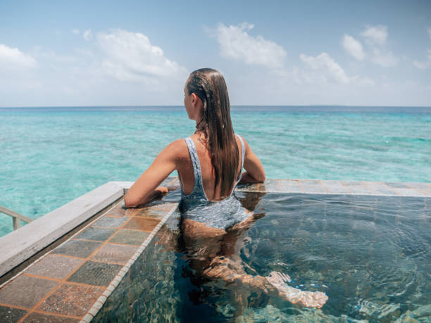 istock Woman relaxes inside infinity pool over reef lagoon 1364617394