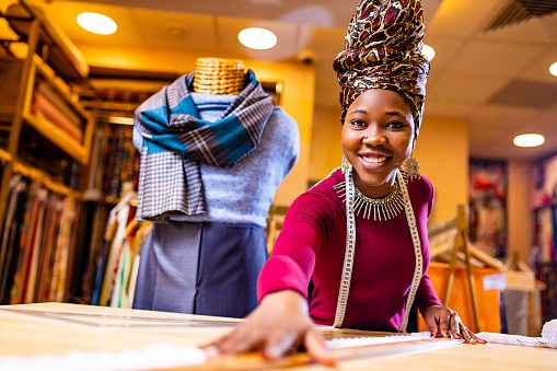 tanzanian woman with snake print turban over hear working in fabrics shop.