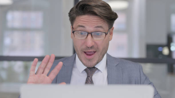 istock Middle Aged Man Talking on Video Call on Laptop in Office 1364618311