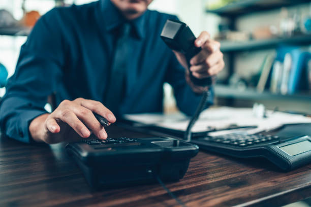 hombre de negocios marcando teléfono de escritorio en la oficina. marcación telefónica, contacto y atención al cliente. - marcar usar el teléfono fotografías e imágenes de stock