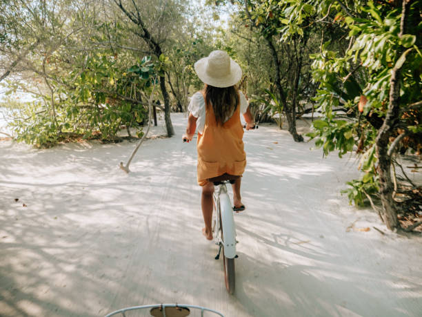 istock Young woman riding bicycle on white sand island 1364618645