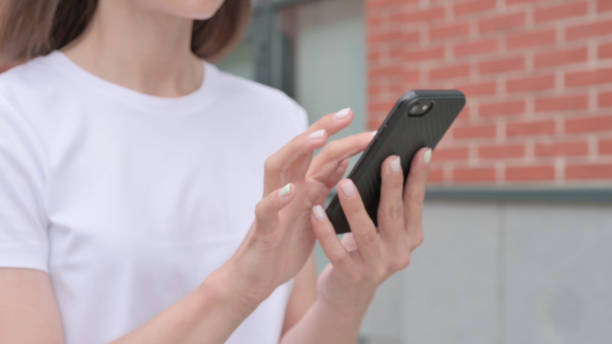 istock Beautiful Woman Browsing Internet on Smartphone on Street 1364621128