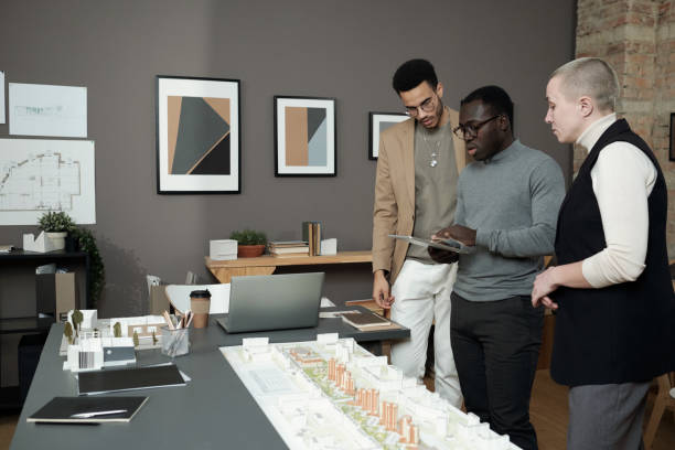 istock Three creative designers or architects discussing layout at meeting 1364621568