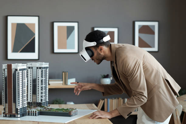 istock Young biracial businessman bending over table and pointing at house layout 1364621617