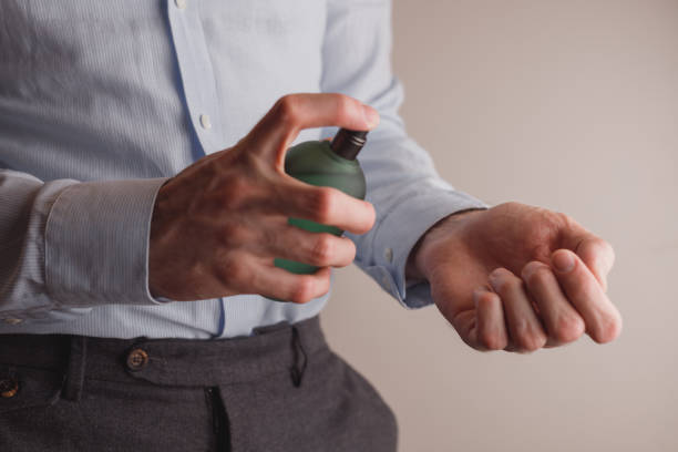 Man in formal wear holding perfume bottle, closeup. Space for text