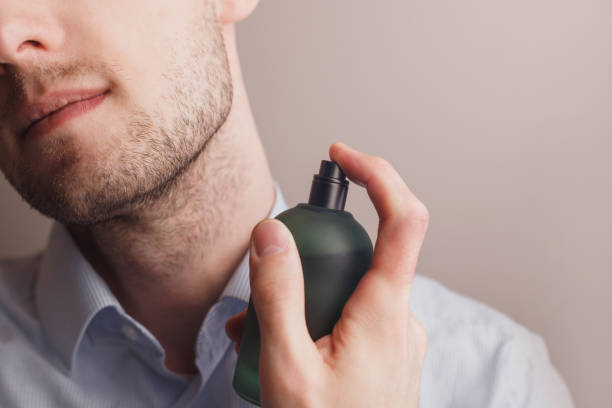 Handsome unshaven man applying perfume on neck, closeup. Space for text stock photo