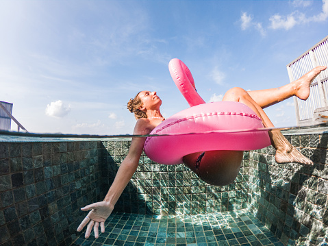 Luxury tropical winter holidays. Woman plays in swimming pool with inflatable flamingo. Maldives