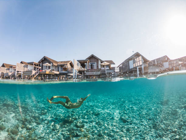 Man dives in tropical sea, split screen underwater shot, overwater villas on background He explores the reef around the atoll in the Maldives, people on vacations, he adventures underwater vacation rental mask stock pictures, royalty-free photos & images