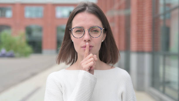 istock Young Woman Showing Quiet by Finger on Lips 1364624182