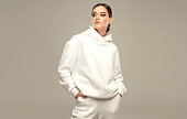 White hoody and sport pants on the perfectly looking young woman wearing in splendid makeup. Fashion and sport.