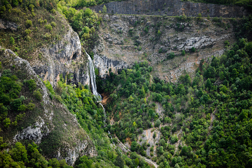 Color photography of aerial view of the Culaz waterfall in summer in middle of beautiful lush foliage countryside. This image was taken near the small village of Cerdon, in Bugey mountains, in Ain, Auvergne-Rhone-Alpes region in France.