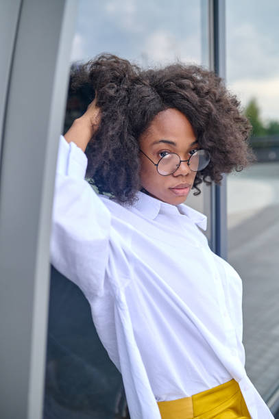 istock Woman with eyeglasses looking at camera leaning on building 1364634657