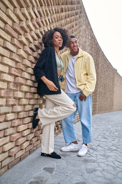 istock Woman and man standing leaning against brick wall 1364634709